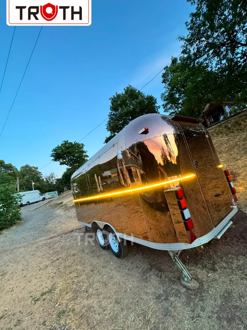 Reflective rose gold streamlined food trailer with warm LED lighting